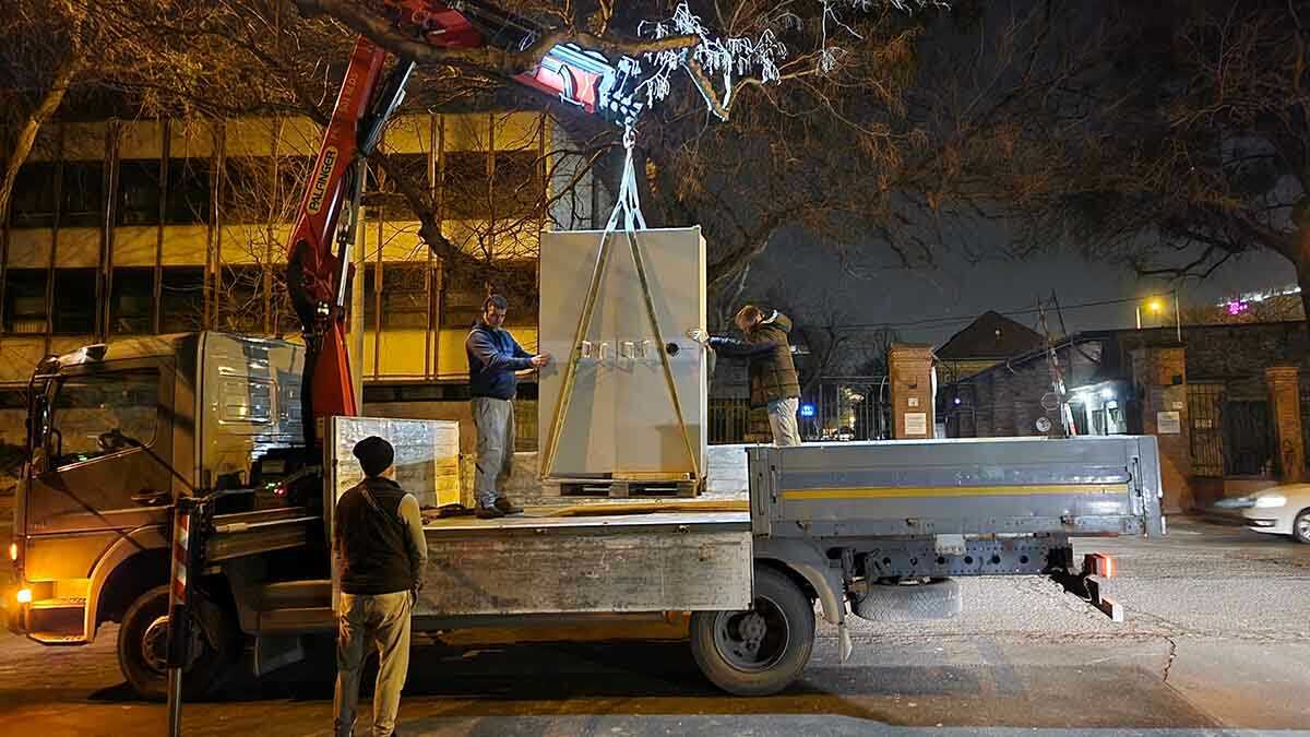 Nehéz páncélszekrény daruzása teherautóról éjszakai munkavégzés során