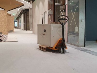 Pultkassza típusú páncélszekrény szállítása békával egy bevásárlóközpont folyosóján