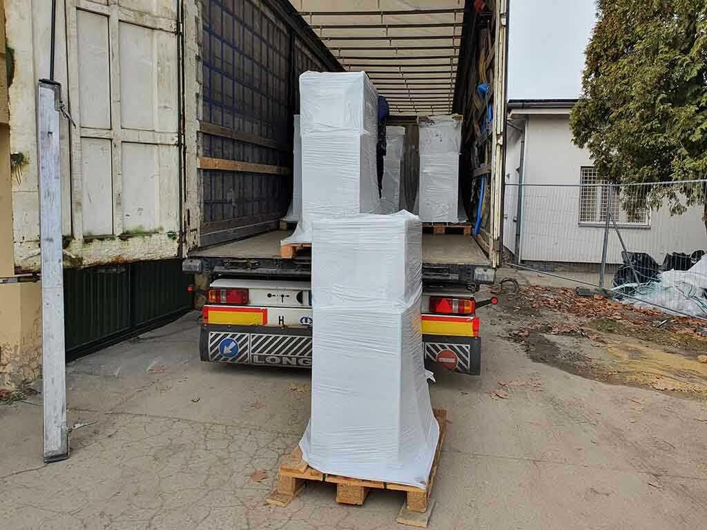 Fóliázott raklapos áru felrakodása ponyvás teherautóba raktérben