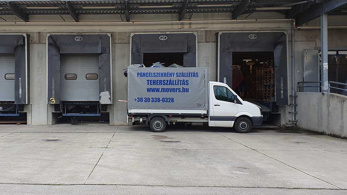 Teherszállítás rakodórámpánál – ponyvás teherautó raklapos áruszállításhoz